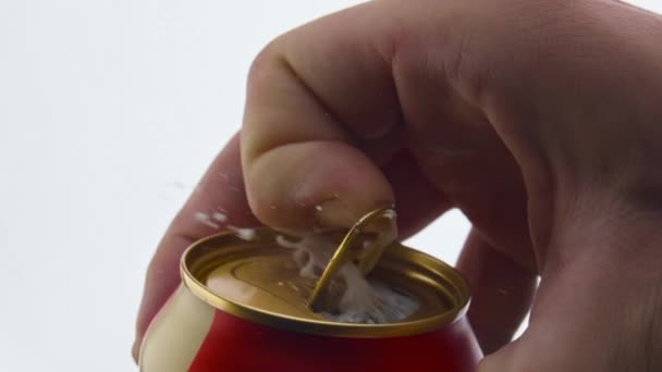 Unknown man opening aluminum beer can in super slow motion close up. Bubbling foam pouring out from canakin with light steam at white background. Wheat alcohol beverage foaming. Brewery concept. - Footage, Video