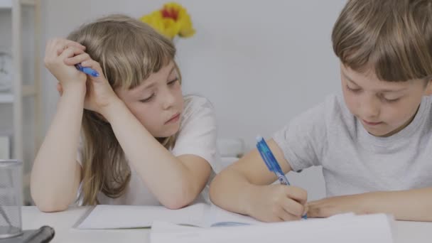Αγόρι 9 ετών βοηθάει τη μικρότερη αδερφή του να κάνει τα μαθήματά της. Υψηλής ποιότητας 4k πλάνα - Πλάνα, βίντεο