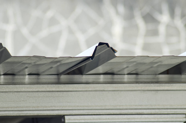 techo de acero ligero. borde lateral de zinc corrugado del techo del edificio. detalle de la cubierta superior de amianto de color plata con fondo borroso - Foto, Imagen