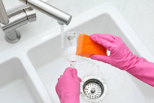 Woman washing glass with sponge in kitchen sink, above view - Zdjęcie, obraz