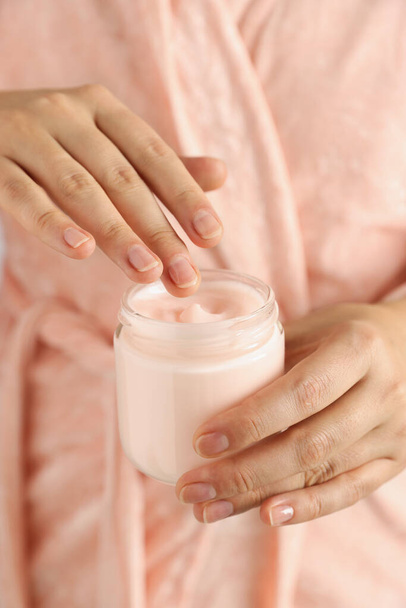 Woman holding jar of hand cream, closeup - 写真・画像