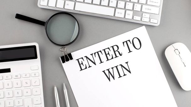 ENTER TO WIN written on paper with office tools and keyboard on grey background - Photo, Image