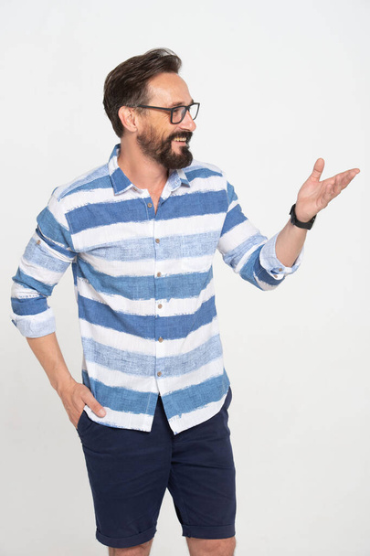 Caucasian man in glasses showing welcome gesture. Handsome Middle-age male model spreading hand, smiling and talking. Portrait, studio shot, gesture concept isolated on white background - Fotoğraf, Görsel