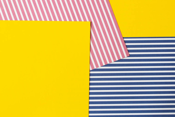 概要幾何学的なファッションカラーの紙の質感の背景。赤、青、白のストライプとテキストのためのコピースペースと空白の黄色の紙の背景を持つストリップ紙。トップビュー、フラットレイアウト. - 写真・画像