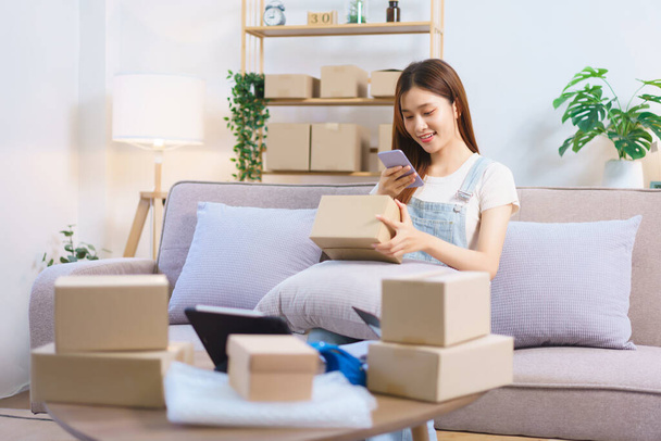 Online trader concept, Female entrepreneur use smartphone to take a picture parcel boxes to client. - 写真・画像