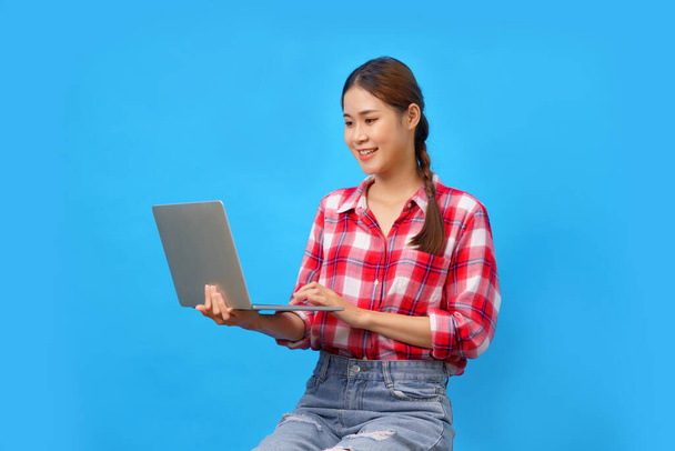 A nők mosolyognak, miközben tartja laptop gépelés adatok új üzlet elszigetelt világoskék háttér. - Fotó, kép