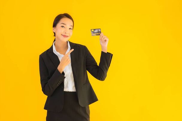 Портрет красивый молодой бизнес азиатской женщины с кредитной картой на желтом фоне изолированы
 - Фото, изображение