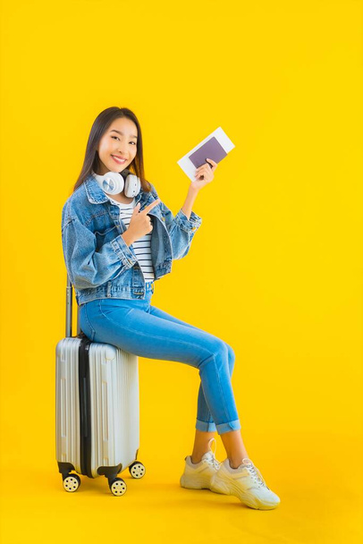 Portrait beautiful young asian woman travel and leisure with luggage bag and passport , boarding pass on yellow isolated background - Foto, afbeelding