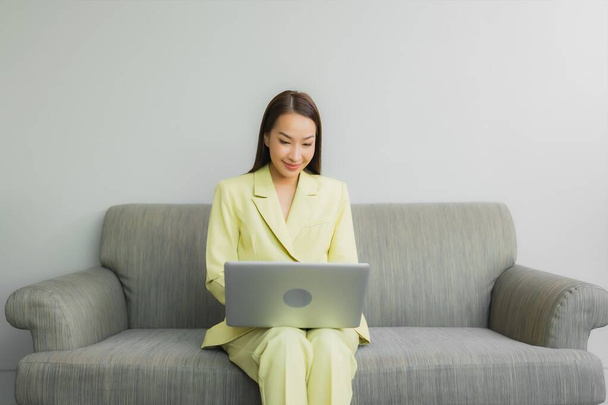 Portré gyönyörű fiatal ázsiai nő használja számítógép laptop kanapén a nappaliban belső - Fotó, kép