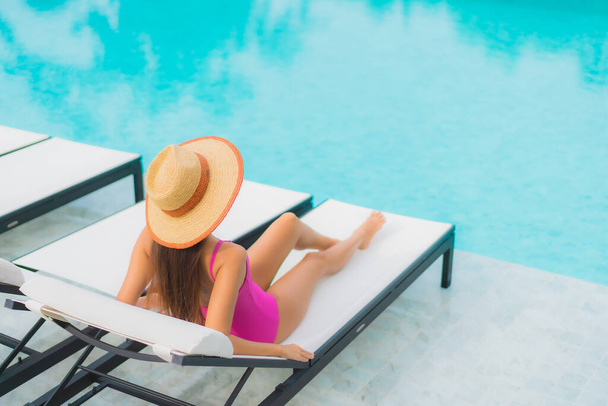 Retrato hermosa joven mujer asiática relajarse sonrisa alrededor de la piscina al aire libre en el complejo hotelero para vacaciones de viaje - Foto, imagen
