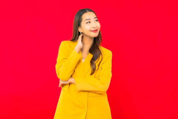 Portrait belle jeune entreprise asiatique femme sourire avec action sur fond rouge isolé - Photo, image