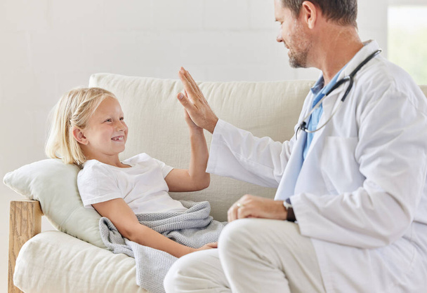 Youre a champ. a male doctor visiting a little girl at home - Foto, Bild