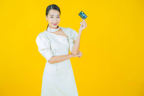 Retrato hermosa joven asiática mujer sonrisa con tarjeta de crédito en color de fondo - Foto, imagen