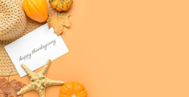 Tarjeta de felicitación con texto FELIZ AGRADECIMIENTO, sombrero de playa con hojas de otoño y calabazas sobre fondo naranja con espacio para texto - Foto, Imagen