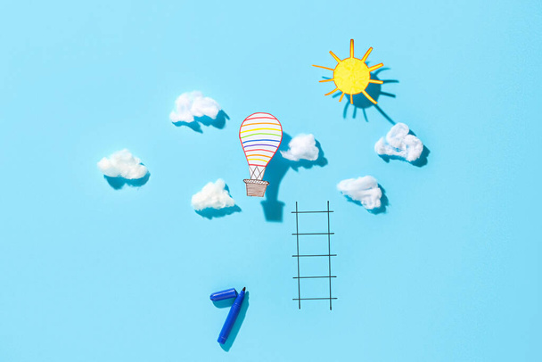 Облака, солнце, воздушный шар и чертеж лестницы на цветном фоне - Фото, изображение