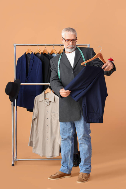 Starší módní návrhář s kalhotami na béžovém pozadí - Fotografie, Obrázek