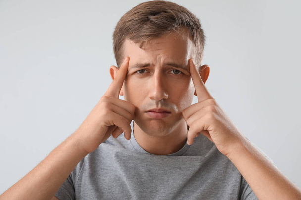 Stressed young man on light background, closeup - Photo, image