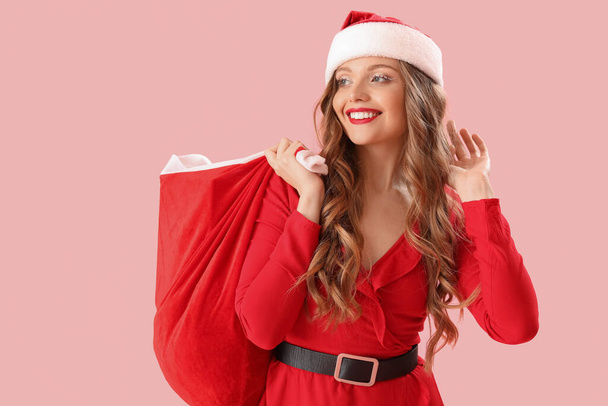 Nuori nainen Santa hattu laukku vaaleanpunainen tausta - Valokuva, kuva