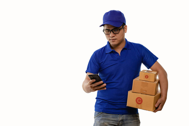 Immagine di felice giovane uomo in cappello blu e blu t-shirt in piedi con scatole gialle isolate su sfondo bianco, concetto di consegna. - Foto, immagini