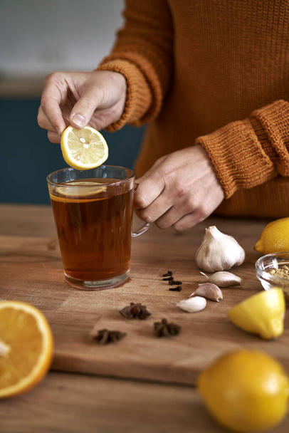 Primer plano de la mujer caucásica añadiendo limón al té  - Foto, imagen