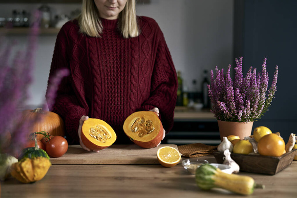 Close up of ripe pumpkin at kitchen's table in woman's hand - Photo, Image