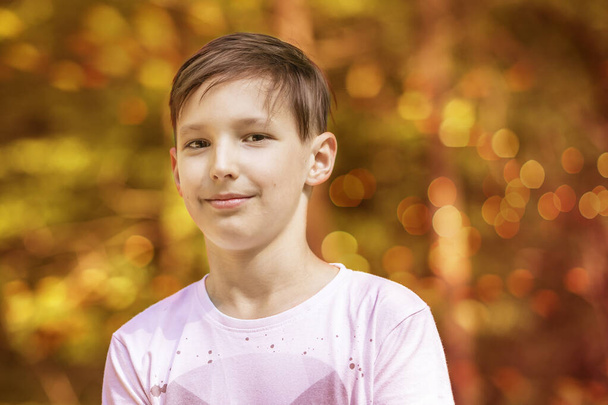 Egy körülbelül 11 éves fiú portréja. Szép bokeh a háttérben. - Fotó, kép