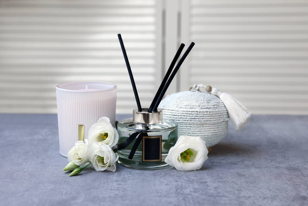 Reed diffuser, scented candle, box and eustoma flowers on gray marble table - Foto, imagen