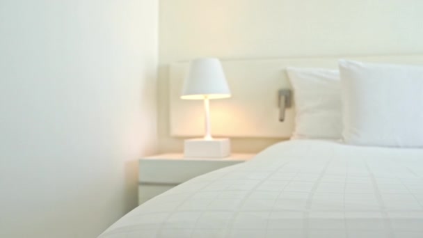 Белые подушки и одеяло на кровати украшают интерьер спальни отеля  - Кадры, видео