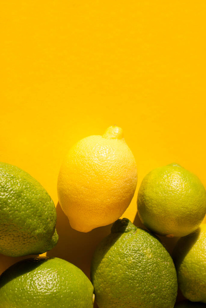 Yellow and green lemons fruit on yellow background with hard shadows. Citrus fruits. Top view, flat lay. Space for text. Green living and eco-friendly products - Foto, Imagen
