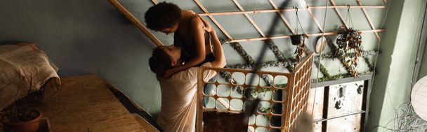 vista de ángulo alto de los jóvenes artistas interracial abrazando cerca de celosía decorativa en el taller, pancarta - Foto, imagen
