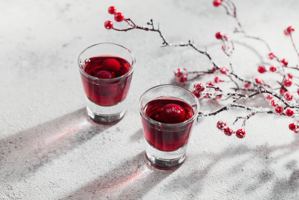 Two glasses of red cocktail, vodka or liqueur on light background. Alcohol shot drink concept - Фото, изображение