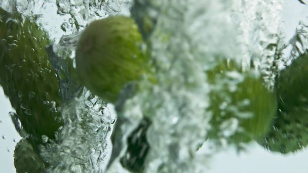 新鮮なキュウリの滝の水を閉じます。季節の庭の野菜が流れる泡状の透明な液体を落とす。薄い背景においしい有機野菜.美しい健康的な料理の商業. - 写真・画像
