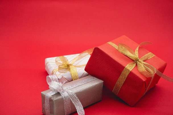 Drei Geschenkboxen, rot, grau und weiß. Nahaufnahme auf rotem Hintergrund. - Foto, Bild