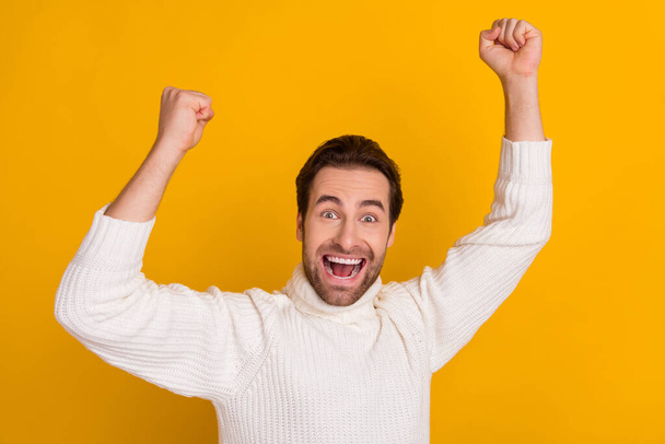 Photo of crazy astonished guy raise hands celebrate goal attainment wear white sweater isolated yellow color background. - Foto, afbeelding