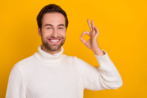 Foto van betrouwbare positieve man toon okey teken goed te keuren oplossing slijtage witte trui geïsoleerde gele kleur achtergrond. - Foto, afbeelding