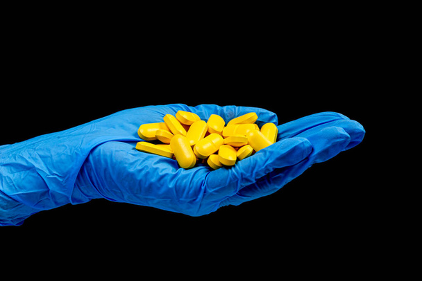 Tabletki medyczne w blistrze na odizolowanym czarnym tle z odbiciem w dłoni, naturalny suplement organiczny bio - Zdjęcie, obraz