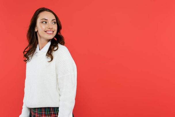 Smiling woman in white jumper looking away isolated on red  - Foto, Imagen