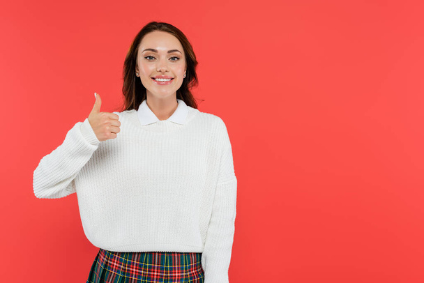 Young woman in cozy jumper showing like gesture isolated on red  - Foto, imagen