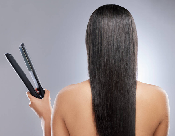 Im definitely a straight girl. Rearview shot of a woman with sleek hair holding a hair straightener - Фото, изображение