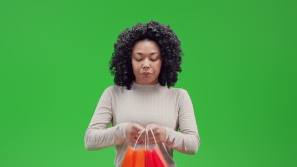 Afrikanische Amerikanerin unzufrieden beim Betrachten von Paketen mit Geschenk Isolated on Green Scree - Filmmaterial, Video