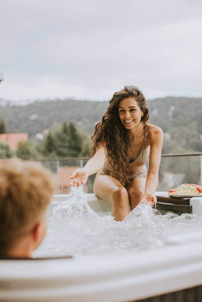 Attractive young couple enjoying in outdoor hot tub on vacation - Valokuva, kuva