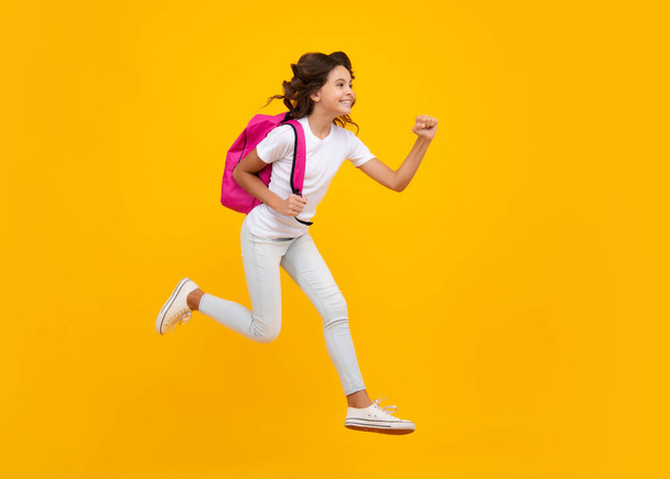 Amazed teen girl. Back to school. Teenage school girl ready to learn. School children on yellow isolated background. Run and jump. Excited expression, cheerful and glad - Foto, Imagen
