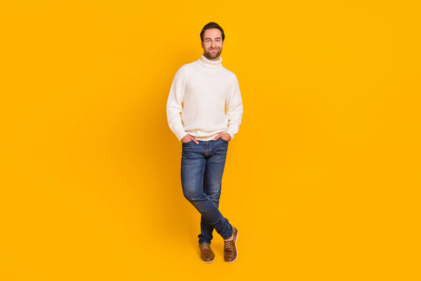 Photo of positive guy hands pockets posing wear white pullover jeans shoes isolated yellow color background. - Φωτογραφία, εικόνα