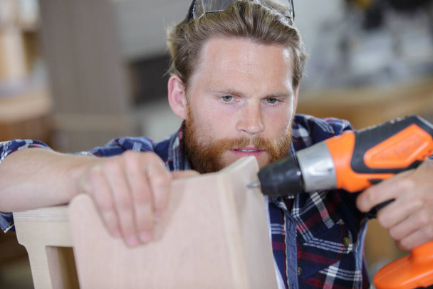 man screwing a wood furniture - Fotoğraf, Görsel
