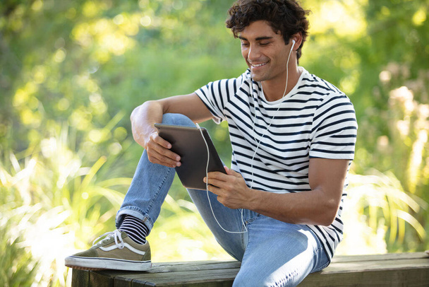 young happy man with headphones tablet pc in city park - Foto, Bild