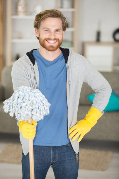 miling man with mop and detergent at home - Foto, immagini