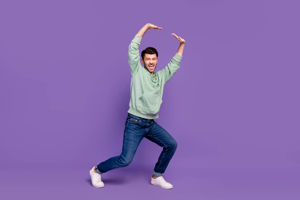 Full body photo of attractive young man lifting empty space struggling wear trendy gray clothes isolated on violet color background. - 写真・画像