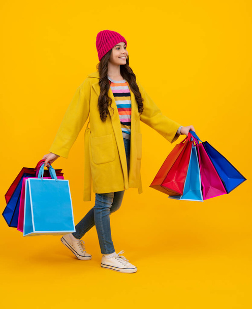 Child girl hold shopping bag enjoying sale isolated on yellow background. Portrait of teenager girl is ready to go shopping. Autumn shopping sale - Fotoğraf, Görsel