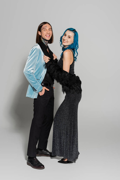 tattooed queer person standing with hand in pocket near elegant nonbinary friend on grey background - Fotografie, Obrázek