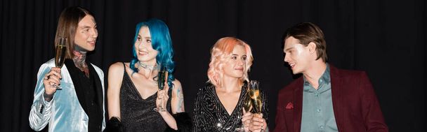 elegant and happy queer people holding champagne glasses and talking on black background, banner - Φωτογραφία, εικόνα